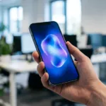 Celular na mão com ícone brilhante de assistente de inteligência artificial na tela, em escritório moderno