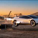Carro esportivo preto e angular girando no ar após sair de uma rampa, com jatos de gás saindo dos propulsores